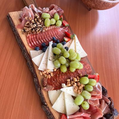 Charcuterie board with meats, cheeses, fruits, and nuts on a wooden board.