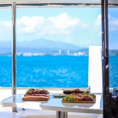 Yacht interior with table set for dining, ocean and mountains visible through window.
