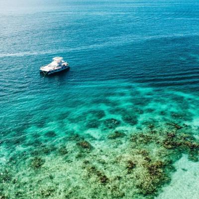 Boat on clear blue ocean near coral reef.