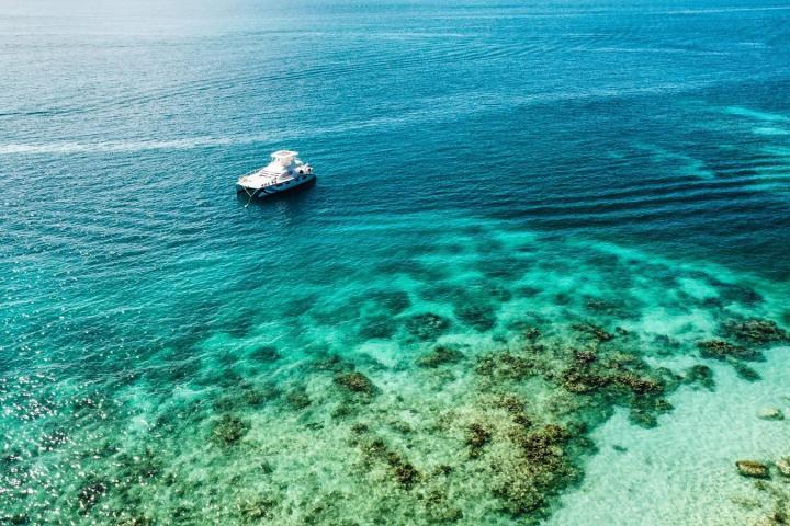 Boat on clear blue ocean near coral reef.