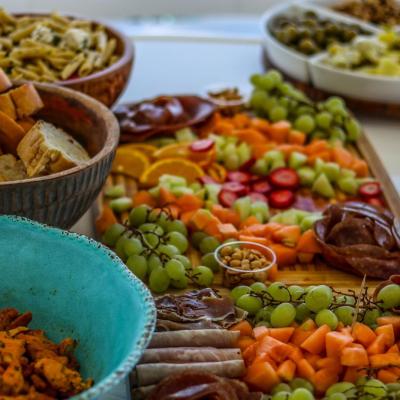 Colorful charcuterie board with fruits, nuts, meats, and breads.