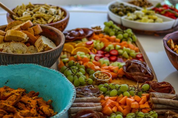 Colorful charcuterie board with fruits, nuts, meats, and breads.